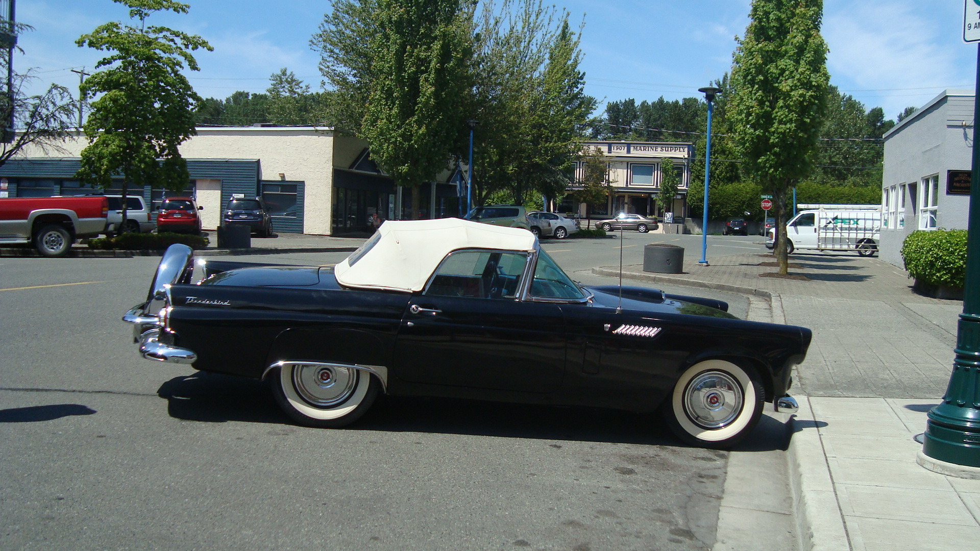Black 1955 Ford Thunderbird convertible parked on a street in Ladner village, Delta BC
